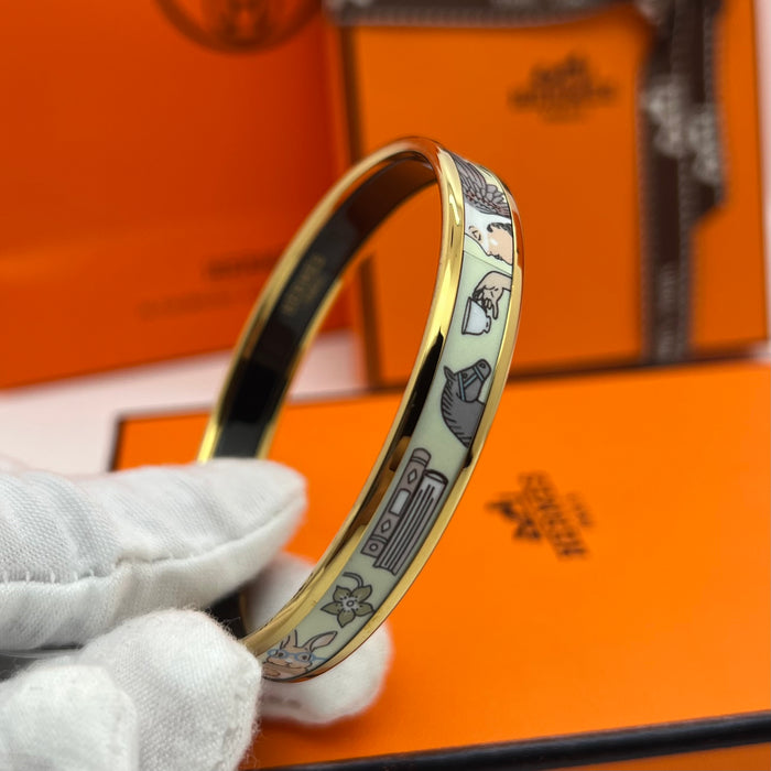 Hermès Enamel Bangle Bracelet
 Color: Light mint green/blue(off-white  background with black, grey, blue, and brown illustrations; black interior lining; gold trim)