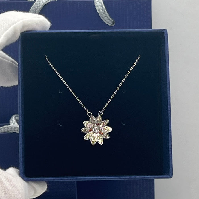 Swarovski Idyllia Daisy / Sunflower Pendant Necklace  
 Color: Silver-tone with pale yellow/champagne pavé petals, a central clear crystal, and contrasting amber-orange crystal accents