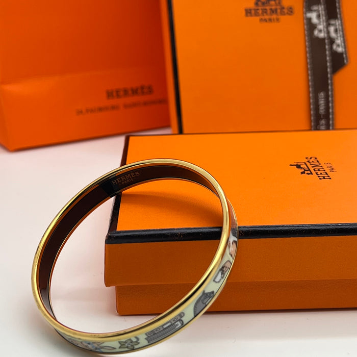 Hermès Enamel Bangle Bracelet
 Color: Light mint green/blue(off-white  background with black, grey, blue, and brown illustrations; black interior lining; gold trim)