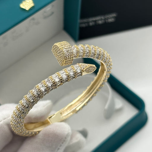 Gold bracelet with diamond accents held by a gloved hand.